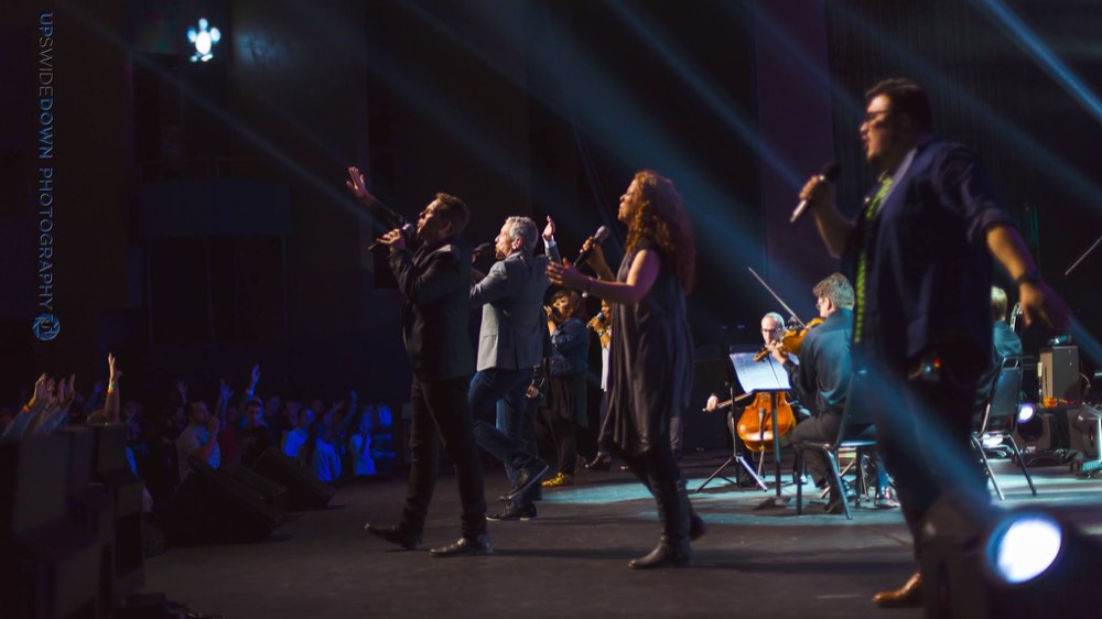 Singers and musicians performing on a blue-lit stage