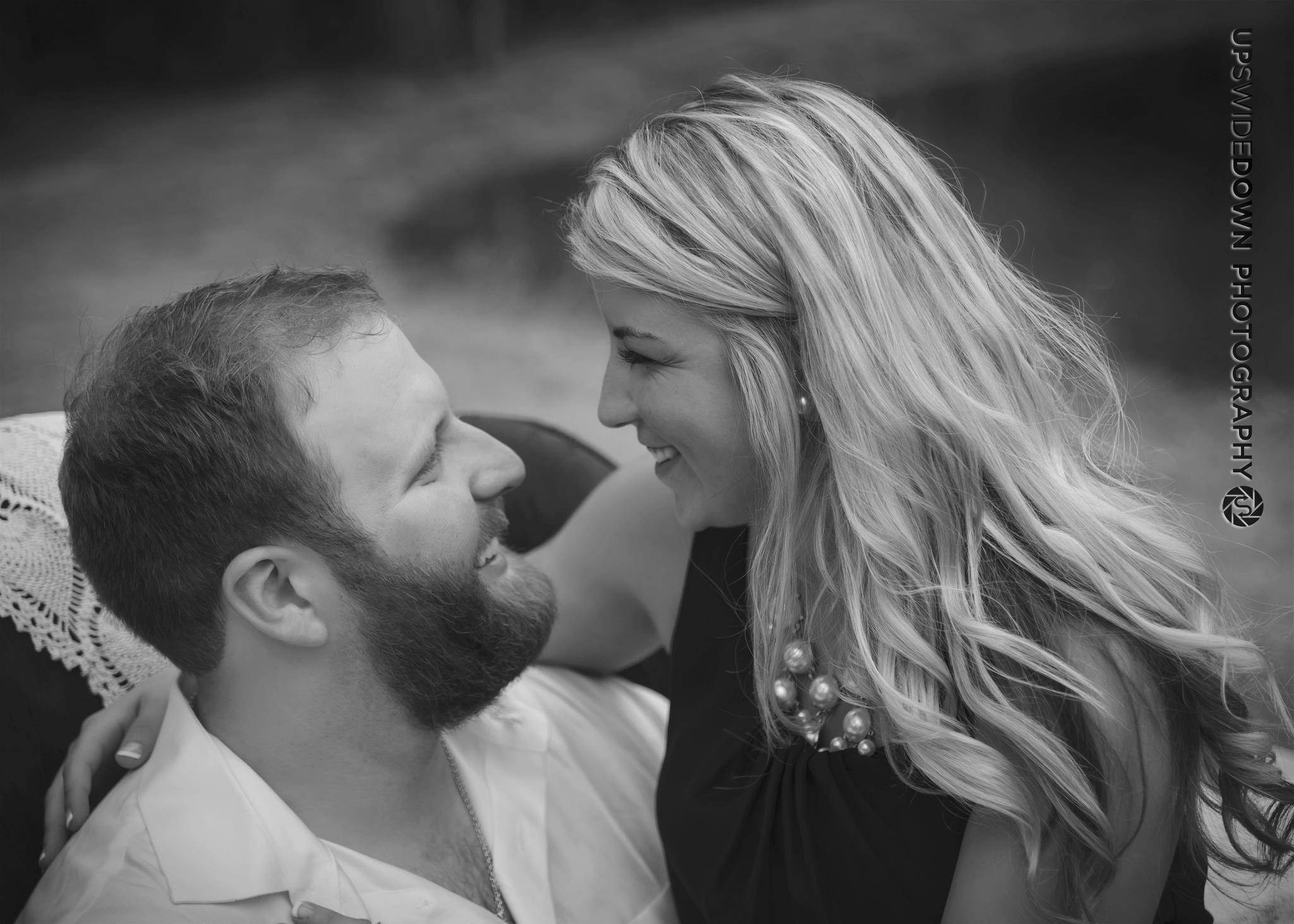 Black-and-white engagement portrait of a couple smiling at one another